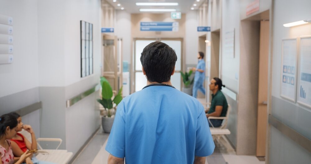 Backview,Shot,Of,Young,Male,Doctor,Walking,In,Hospital,Corridor.
