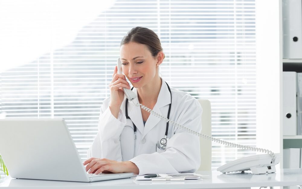 Beautiful,Female,Doctor,Talking,On,Land,Line,Phone,While,Using